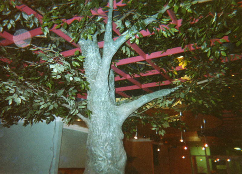 Immersive café interior with a sculpted tree trunk and canopy of silk foliage